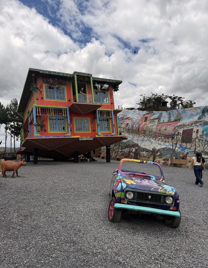La Casa al Revés con un auto pintado de colores en primer plano