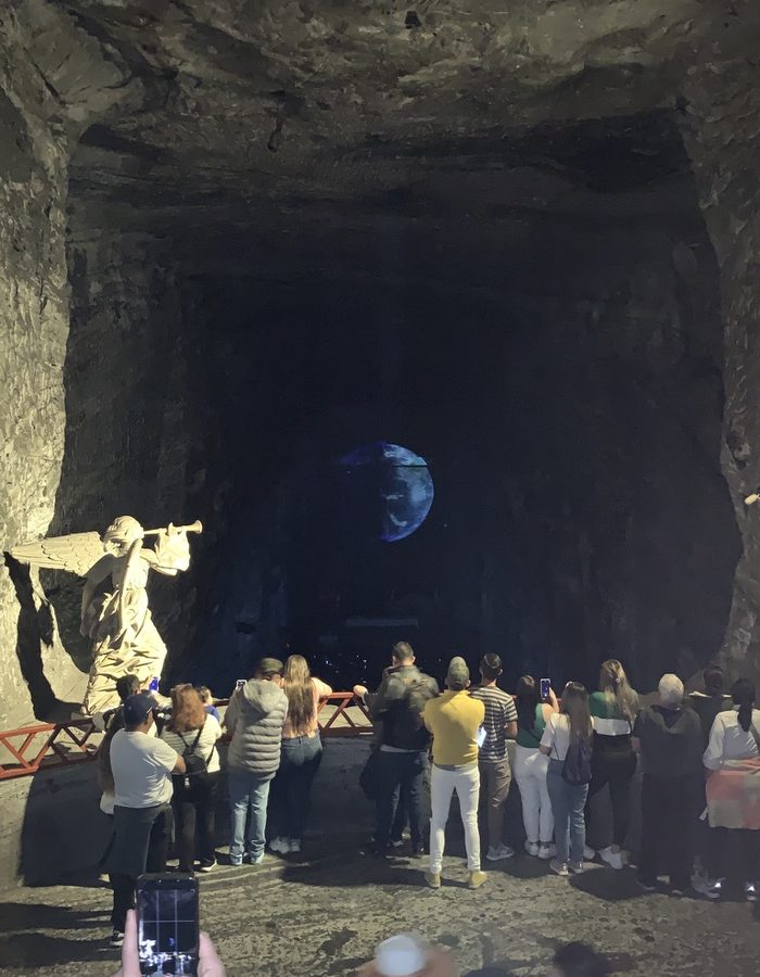 Escultura de ángel con trompeta junto a una esfera azul iluminada, en la Catedral de Sal