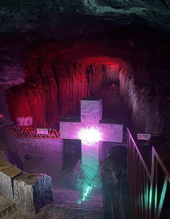 Cruz tallada en sal iluminada en tonos rojos y turquesa, en la Catedral de Sal